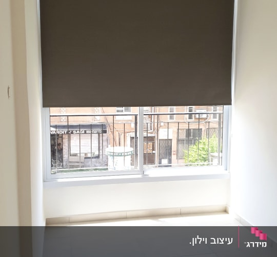 וילון גלילה והצללה כהה מותקן על חלון בחדר מגורים
